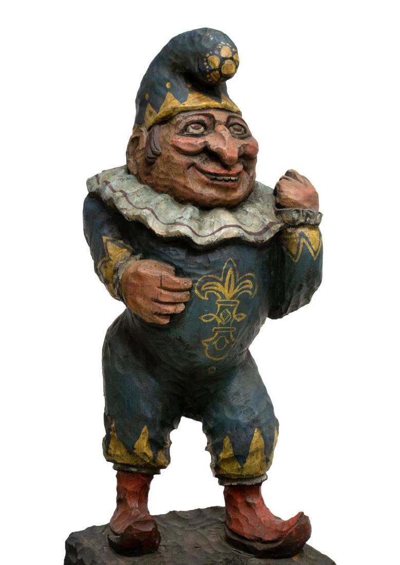 CARVED & PAINTED PUNCH CIGAR STORE FIGURE ON STAND: Carved and painted wood figure, 20th c., after the Punch Cigar advertising mascot, the figure with a stocking hat, neck ruff, suit with a painted fleur-de-lis, and red pointed shoes, on tall plinth ba