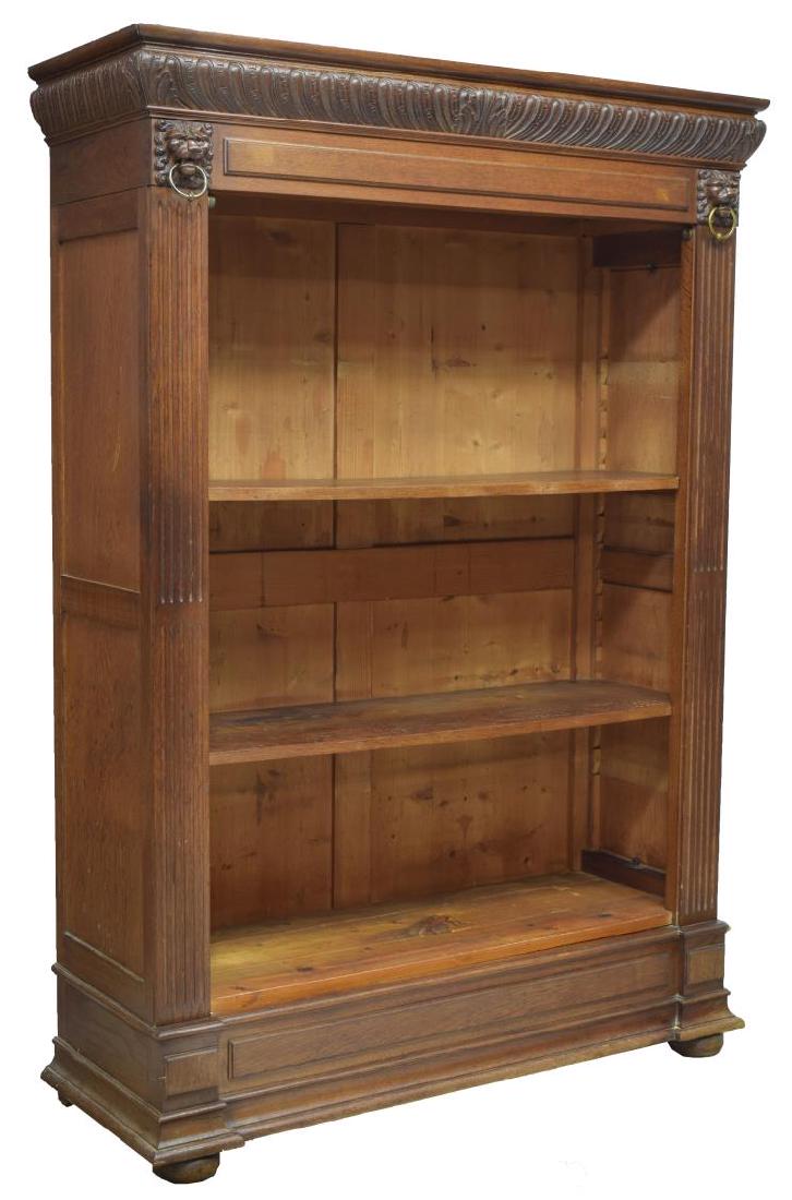 CONTINENTAL OAK BOOKCASE: Continental oak bookcase, with carved gadrooned cornice, over lion's mask brackets holding a metal ring, case fitted with open shelves, flanked by fluted sides, all on plinth base, rising on bun feet,