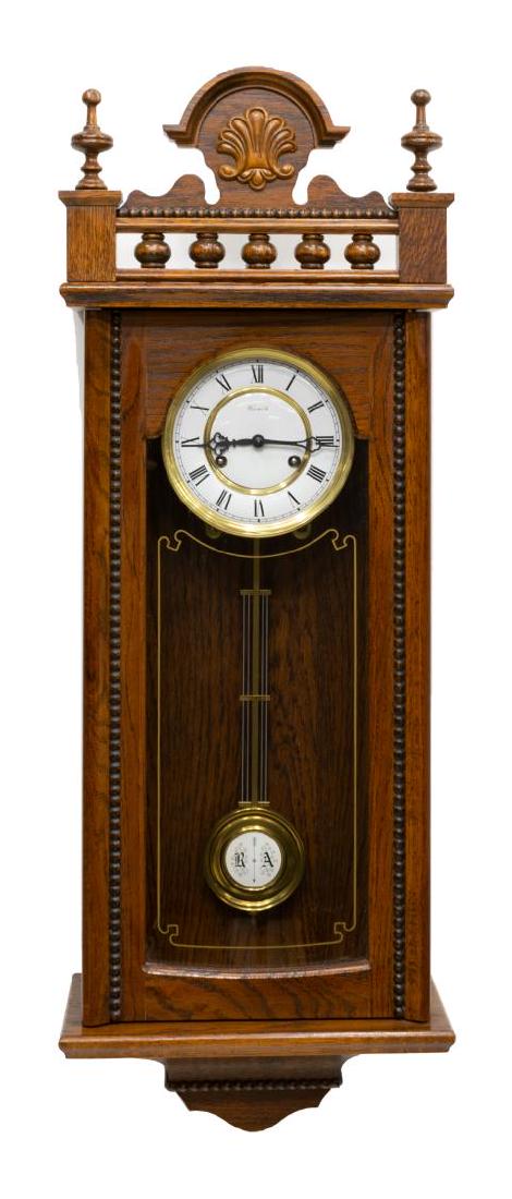 DUTCH WARMINK SPINDLED OAK WALL CLOCK: Dutch oak time and strike hanging wall clock, the enameled dial with Roman numerals marked Warmink, the case having spindled crest and applied carving, pendulum with enameled accent, approx 33"h, 11.5