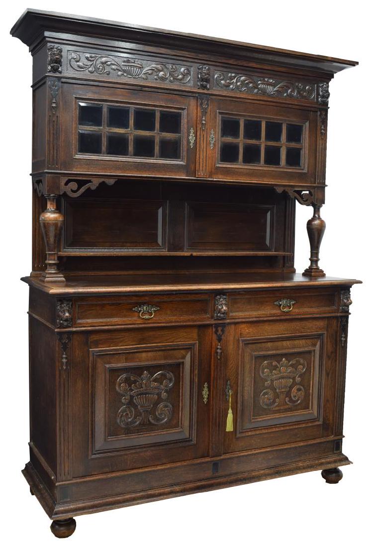CONTINENTAL CARVED OAK SIDEBOARD: Continental oak sideboard, having cornice top, over frieze with carved scrolling foliates and lion masks, upper double-door cabinet with segmented beveled glass doors, supported by turned columns, bac