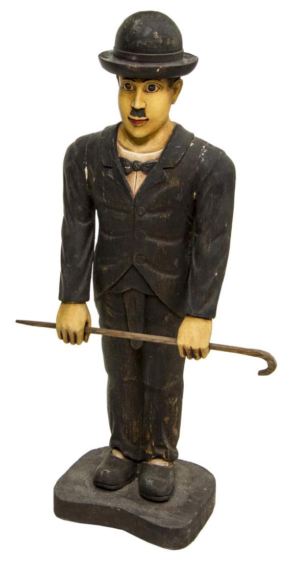 CARVED WOOD FIGURE OF CHARLIE CHAPLIN: Carved wood statue, Charlie Chaplin, wearing top hat and holding a cane, some paint loss, 38"h, 9"l, 20"w, Start Price: $80.00