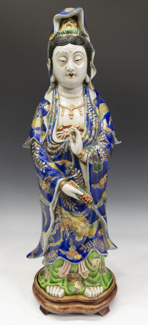 LARGE KUTANI STYLE PORCELAIN FIGURE OF QUAN YIN: Asian Kutani style porcelain figure of Quan Yin, dressed in robes with raised gilding, standing upon a wood base, on base: approx 25"h, 8"w, 7"d, 13lbs Start Price: $250.00