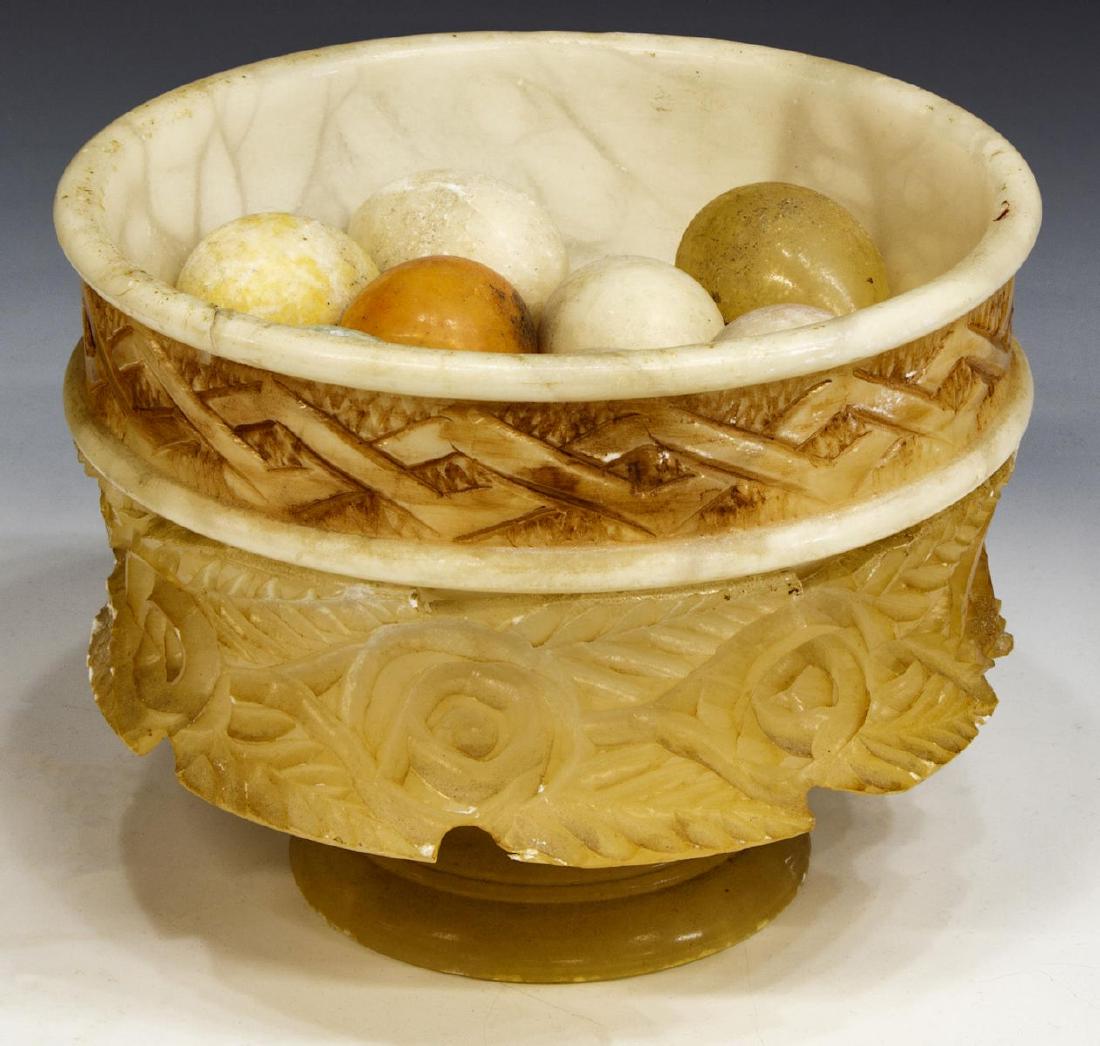 CONTINENETAL CARVED ALABASTER BOWL WITH EGGS: Continental alabaster carved bowl with eggs of various colors, elaborately carved bowl, with running ornamentation and foliate design, holding eight eggs, three eggs fractured but intact, approx 7.75"