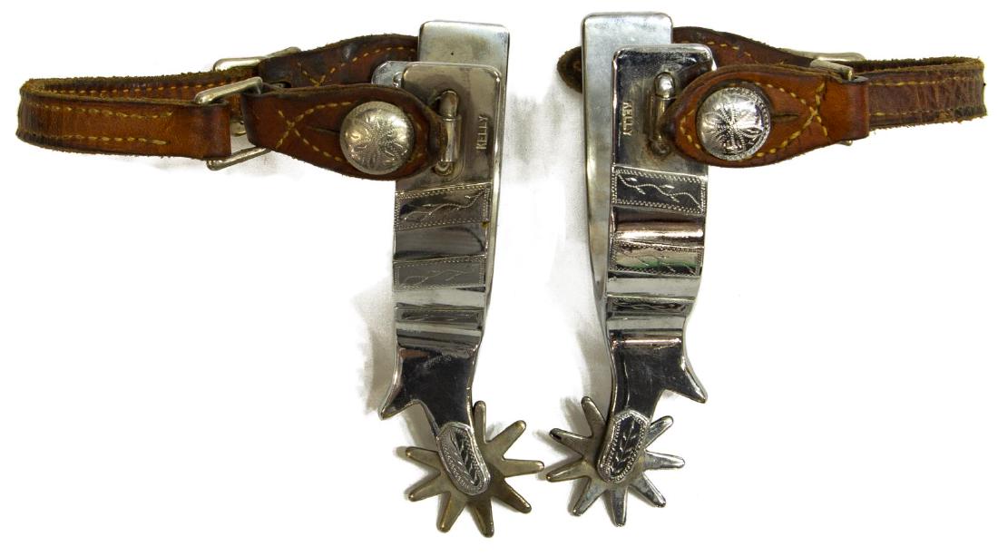 KELLY COWBOY SPURS: Kelly marked cowboy spurs, engraved outside button and shank, mounted nickel silver outside heel, 9 point 1.5" diameter rowels, belt buckle leathers, yoke inside: approx. 3"w, 3.1/8"d, total: 1.5lbs S