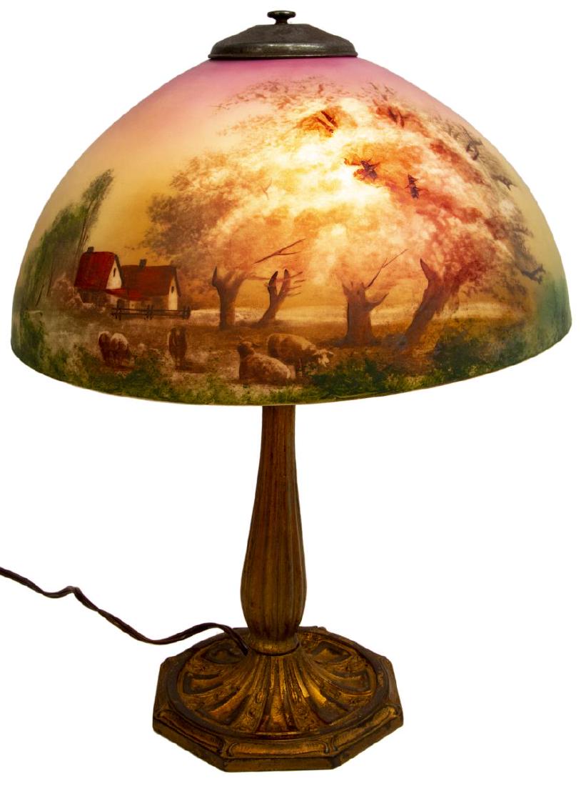 AMERICAN REVERSE PAINTED SUNRISE METAL TABLE LAMP: American reverse painted glass table lamp, early 20thc., showing a pastoral scene with sheep and houses in a landscape scene, dual light sockets, on metal base with remnants of gilding, small chips al