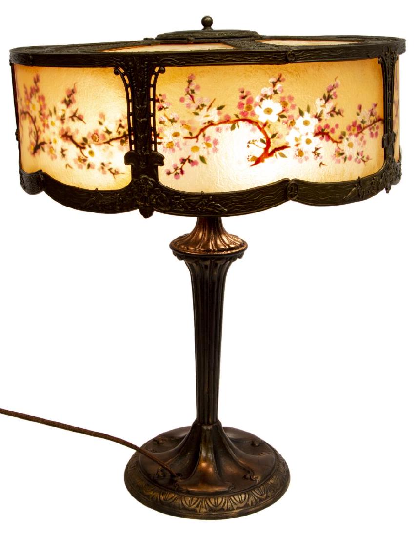 AMERICAN REVERSE PAINTED GILT METAL TABLE LAMP: American reverse painted table lamp, early 20thc., the gilt metal shade detailed with flowers and pendants in relief, reverse painted panels showing flowering branches, dual light sockets, on a gilt m