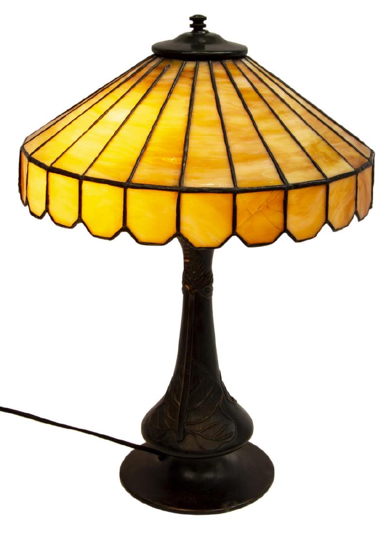 VINTAGE AMERICAN SLAG GLASS & METAL TABLE LAMP: American slag glass table lamp, dual light sockets beneath the caramel and leaded glass shade, dark patinated base with handled leaf motif on a circular foot, approx 21"h, 14.5"diam, 10.5lbs Start Pri