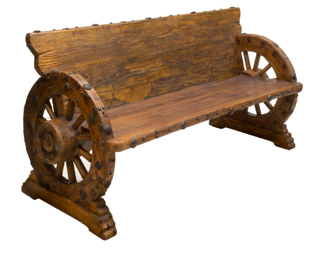 RUSTIC IRON ACCENTED ELMWOOD WAGON WHEEL BENCH: Rustic elmwood bench, late 20th c., accented with various size black iron nail heads, the seat and back flanked by wagon wheels with mortised spokes and protruding axle, 34"h, 69.5", 28"d **Provenance