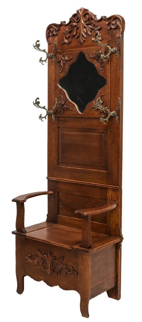 AMERICAN OAK BENCH SEAT MIRRORED HALL TREE: American oak hall tree, 19th c., the crest with applied carving over a shaped miror with flanking ornate coat hooks, shaped arms on either side of the hinged bench seat, raised on shaped feet, 81.5"h,