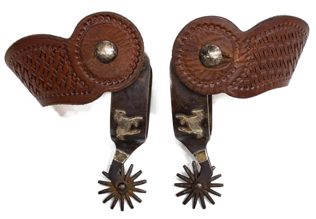 PAUL BOND GALLOPING HORSE SPURS: Paul Bonds spurs, Bayfield, Colorado, each decorated with a nickel galloping horse, 1.75" rowels, tooled leather straps, marked at the interior, inside yoke approx. 3.25"w, 3.25"d Start Price: $100.00