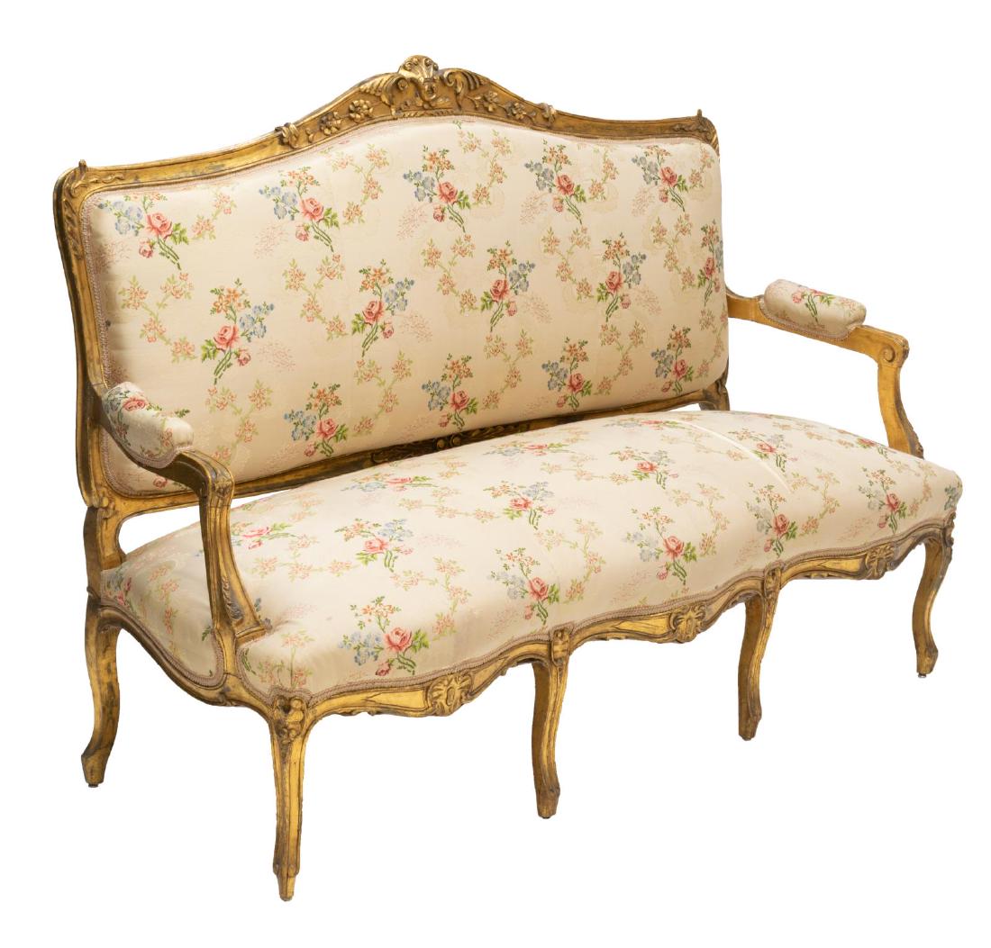 ITALIAN LOUIS XV STYLE CARVED PARLOR SOFA: Italian Louis XV style parlor sofa, 20thc., a foliate carved crest surmounting a padded back, seat, and armrests with floral design, rising on cabriole legs, tear to the seat fabric, approx 44"h, 61"w