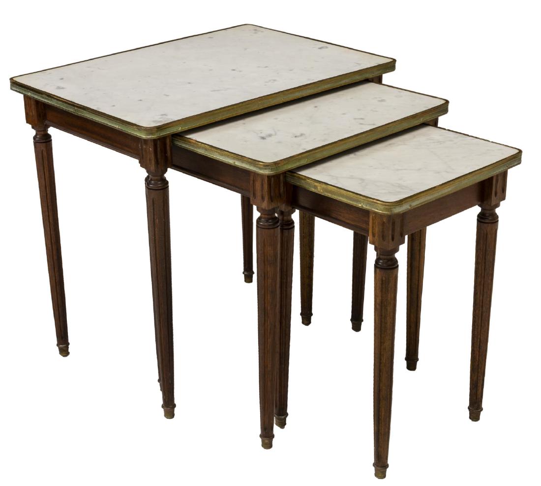 (3) LOUIS XVI STYLE MARBLE TOP NESTING TABLES: French Louis XVI style nest of three tables, 20thc., each having metal bound marble top, rising on fluted legs, ending in metal caps, largest: 21"h, 21.75"w, 15.25"d Start Price: $80.00