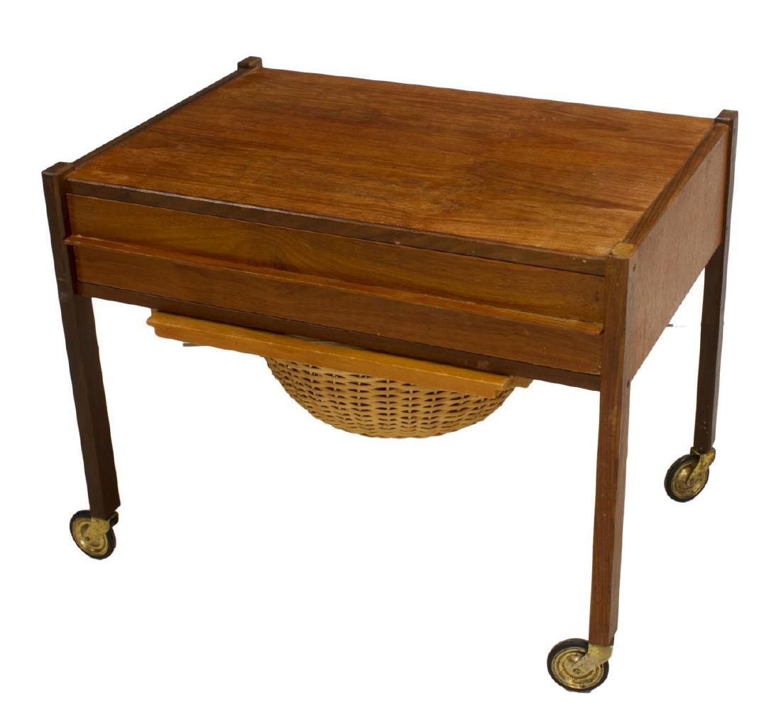 DANISH MID-CENTURY MODERN TEAK SEWING TABLE: Danish mid-century modern teak sewing table, c. 1950s, having single sectioned drawer above pull out wicker basket, rising on legs with wheeled feet, approx 20"h, 25"w, 17"d Start Price: $100.00
