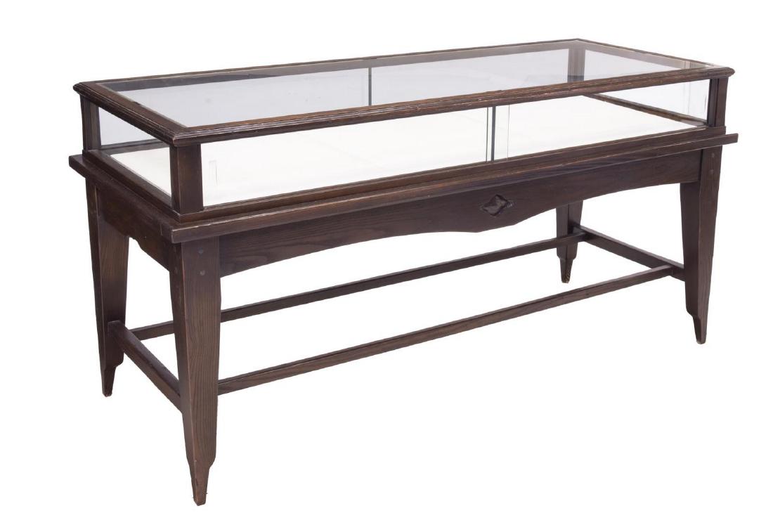 JAMES AVERY OAK JEWLERY RETAIL SHOP DISPLAY CASE: Retail display case, late 20th c., James Avery, oak frame with glazed top and sides, sliding glass doors at front, linen-clad interior display surfaces, rising on stretcher-joined tapered legs, approx