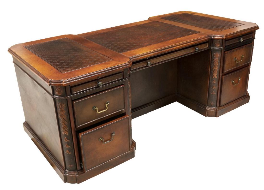 CONTEMPORARY OVERSIZED LEATHER CLAD PARTNERS DESK: Contemporary oversized leather covered, knee hole partners desk, top with inset foliate embossed panels, foliate pendants to corners, central modesty panel, one side with three pull-out writing surfac