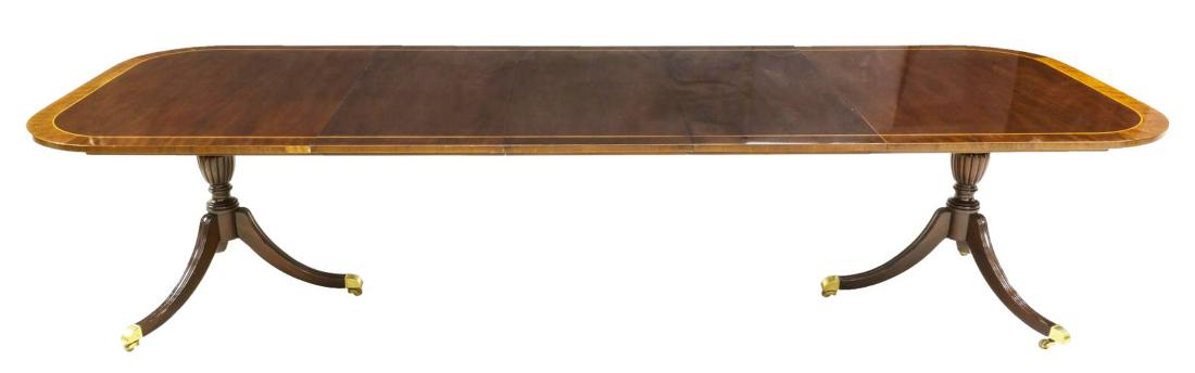 GEORGIAN STYLE COUNCIL MAHOGANY DINING TABLE 128"L: Georgian style dining table by Councill Furniture, late 20th c., mahogany with a contrasting perimeter band, three 20" skirted leaves, rising on two three leg pedestals with brass claw feet on castors