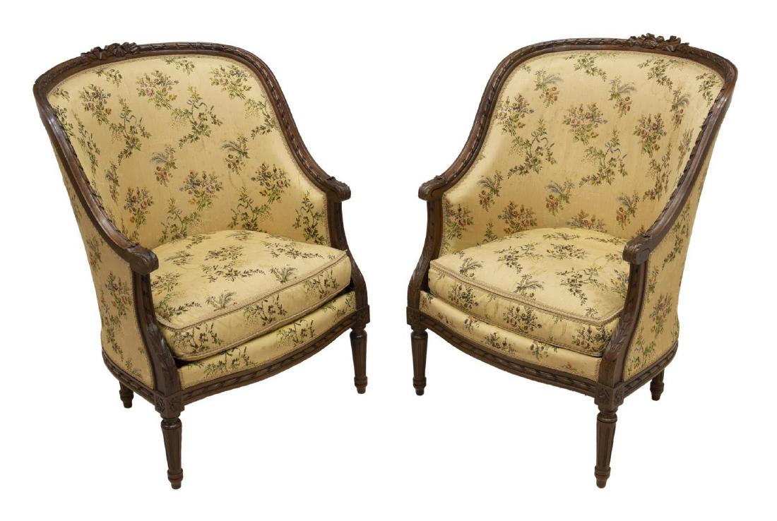 (2) FRENCH LOUIS XVI STYLE BERGERES EN GONDOLE: (lot of 2) French Louis XVI style bergeres en gondole, 19th c., carved ribbon crest, over enclosed back, removable seat cushion, scrolled foliate-carved handholds, rising on tapering fluted legs, wear