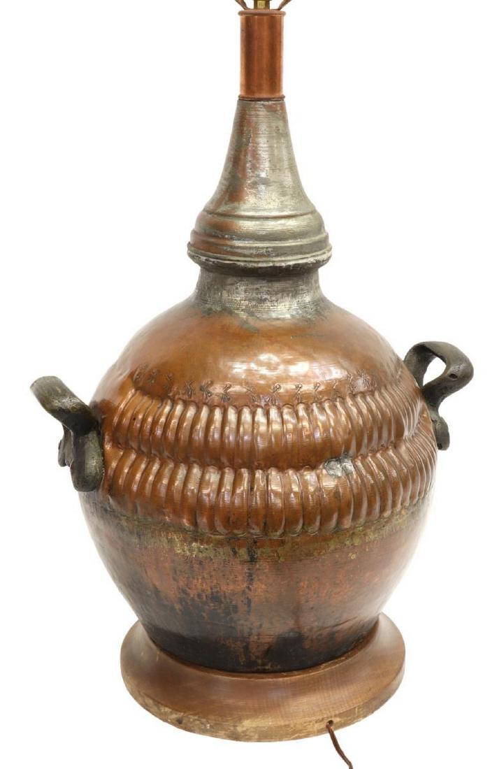 PATINATED COPPER TABLE LAMP: Patinated copper table lamp, made from an antique copper jar, iron handles, rising on a circular wood base, approx. 34.5"h to top of harp, 16"w, 13"d, 17.5lbs Start Price: $100.00