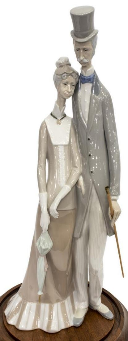 LLADRO PORCLEAIN FIGURE, OLD AGE COUPLE: Lladro porcelain figure, Old Age Couple, designed by Julio Fernandez, retired in 1985, maker's mark underfoot, contained in a glass cloche with wood stand, approx 19"h, 7.25"w, 5"d, 9.5lbs Start Price