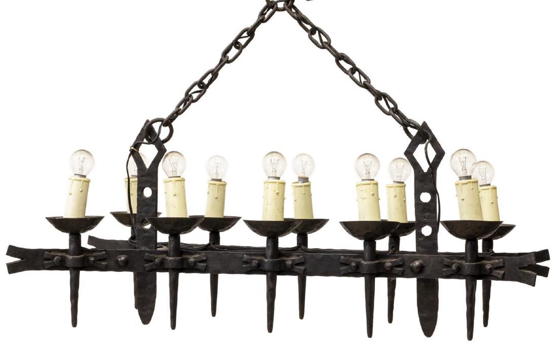 GOTHIC REVIVAL WROUGHT IRON TEN-LIGHT CHANDELIER: Gothic Revival wrought iron chandelier, 20th c., having ten lights in two rows of faux candles, over conical bobeche on tapered standard, suspended from chain by two central vertical supports, fixture