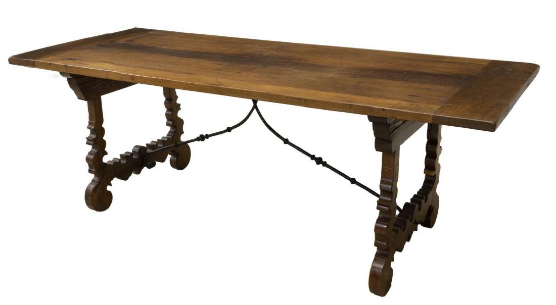 SPANISH BAROQUE STYLE PLANK-TOP TABLE, 96"L: Spanish Baroque style mixed wood table, fashioned from various elements, having plank top with wide boards, rising on ox yoke trestle supports, joined by scrolled iron center stretcher, separation bet