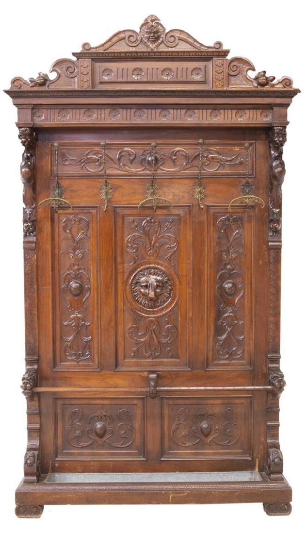 ITALIAN RENAISSANCE REVIVAL HALL TREE STAND: Italian Renaissance Revival hall tree, 19th c., carved with running ornamentation, foliate elements and masks, having five coat hooks above umbrella storage with removable metal drip pan, rising on bl