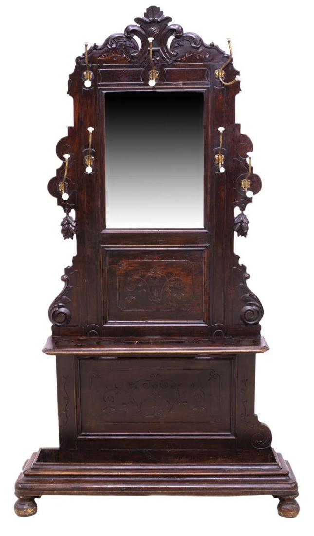 FRENCH CARVED & INSCISED MIRRORED HALL TREE: French hall tree, early 20th c., accented with incised foliate carving, the shaped top over a central mirror with seven porcelain end coat hooks, the lower part with an umbrella stand, rising on bun f