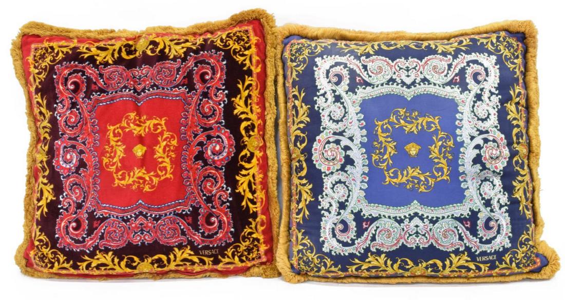 (PR) VERSACE DECORATIVE MEDUSA SILK PILLOWS: (pair) Versace silk pillows, having red ground to one side with blue to alternate, scrollwork pattern with stylized Medusa mask accents, gold fringe, approx 15"l, 15"w, 4.75lbs total **Provenance: Fro