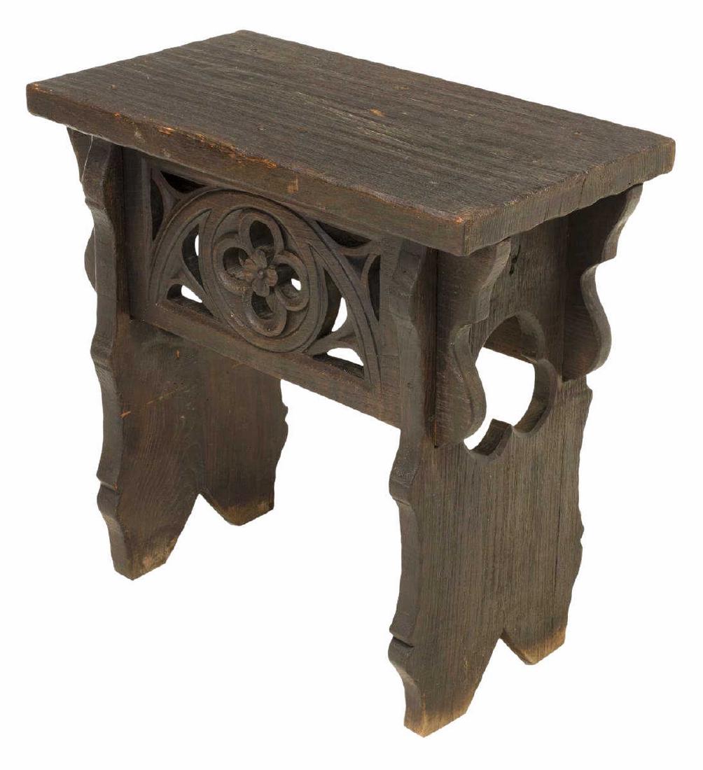 GOTHIC REVIVAL CARVED & PIERCED SIDE TABLE BENCH: Continental Gothic Revival ebonized table/ bench, late 19th c., having thick board top, faced with carved and pierced floral roundel in demilune frame, raised on trestle base with pierced trefoils, bo