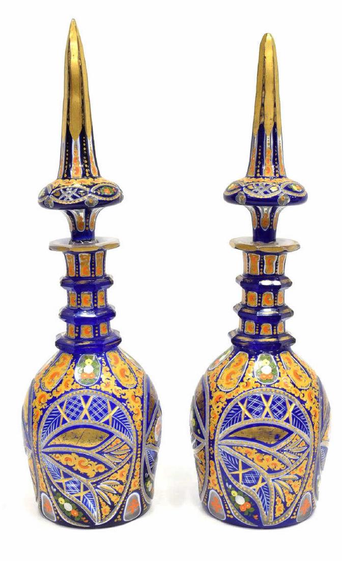 2) BOHEMIAN CASED PARCEL GILT PERSIAN DECANTERS: (pair) Very fine and large Bohemian cobalt cased and enameled art glass decanters, made for the Islamic market, 19thc., each of varied size, having an elongated steeple form stopper resting in a ring 