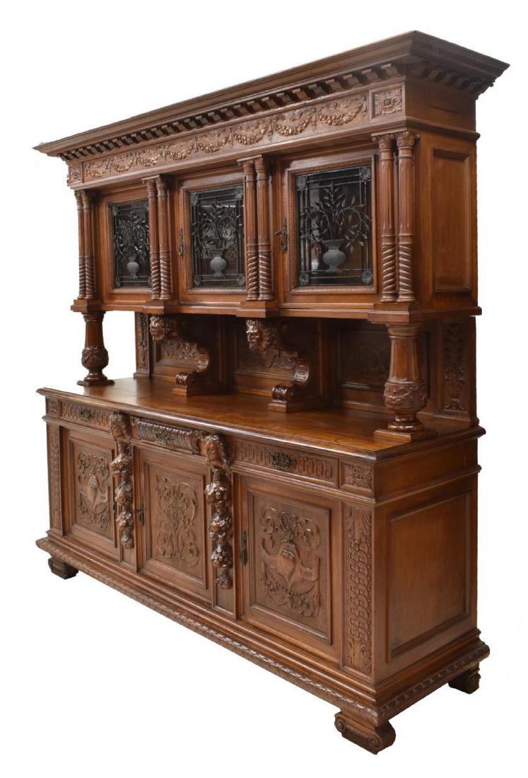 ITALIAN RENAISSANCE REVIVAL CARVED SIDEBOARD: Italian Renaissance Revival sideboard, early 20th c., the upper part with a protruding cornice over the foliate carved frieze, three doors with foliate pattern iron over glass flanked by twist and tur