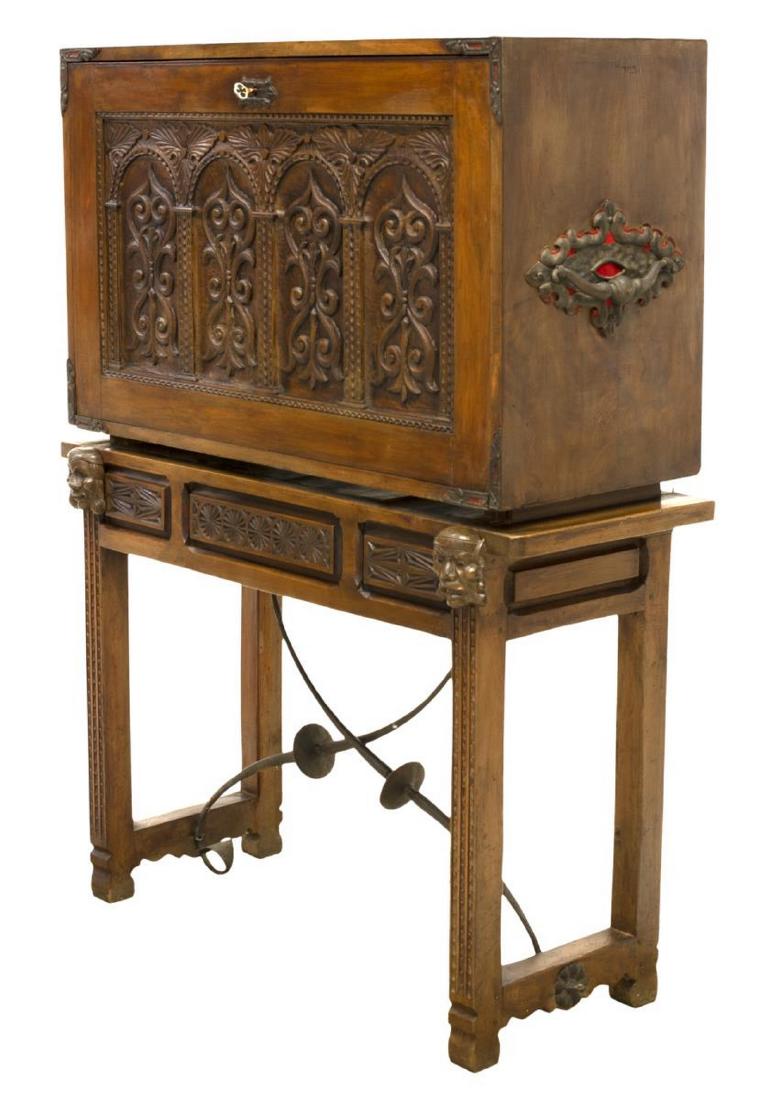 SPANISH CARVED VARGUENO TRAVELING DESK ON STAND: Spanish vargueno or traveling desk on stand, 19th c., having a drop front opening to a writing desk supported by pull out mask faced arms on the stand, the interior with ten drawers and a door, the ou