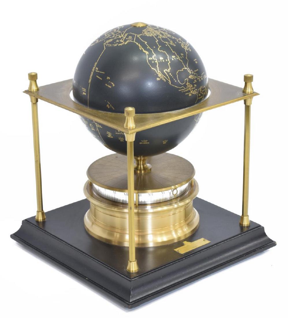 ROYAL GEOGRAPHICAL SOCIETY WORLD CLOCK, 1979: Royal Geographical Society world clock, c. 1979, having globe with gilt accent depicting time zones, supported by brass frame with ring for measuring, twenty-four hour dial beneath with Roman and Arab