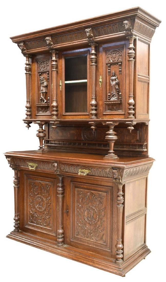 HENRI II STYLE FIGURAL & FOLIATE CARVED CABINET: French Henri II style two part cabinet, 19th c., accented with mask and finials, the upper part with a stepped cornice above a central glazed door flanked by a figural faced door at each side, separat