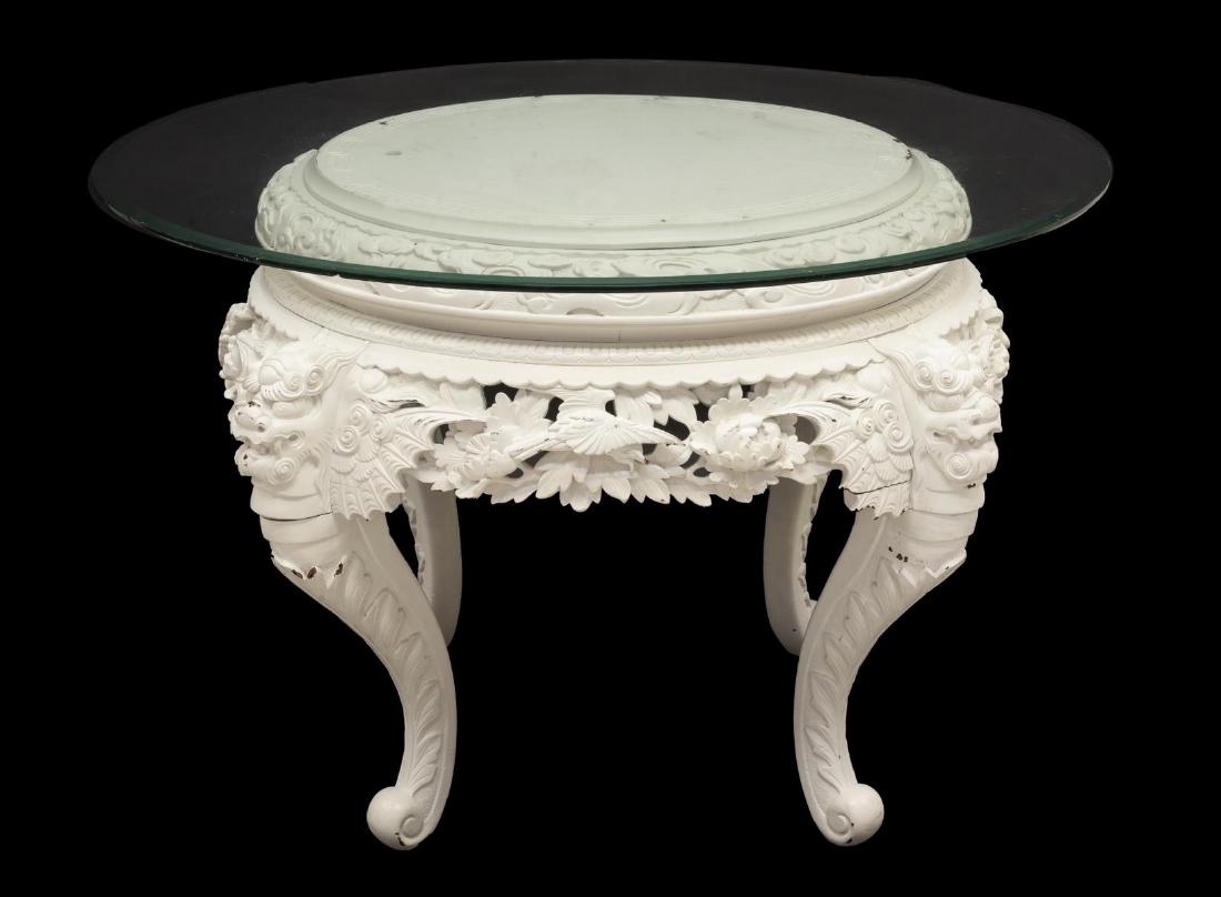 CHINESE GLASS TOP CHIMERA TABLE IN WHITE PAINT: Chinese painted wood pedestal table, 20th c., having a round glass top over base with Greek key pattern, the apron with open work birds and flowers, rising on scrolled chimera form legs, some chips to