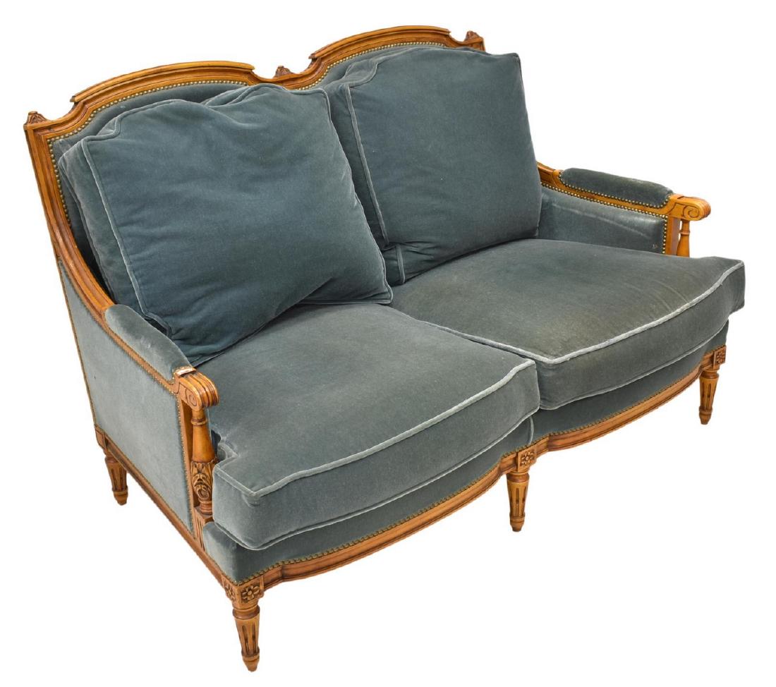 FRENCH LOUIS XVI STYLE TWO-SEAT SOFA SETTEE: French Louis XVI style sofa, early 20th c., in a fruitwood finish, having floral, foliate and scrollwork carving, possible mohair upholstery, accented by brass tacking, turned standards supporting arm