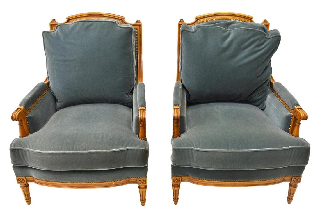 (PR) FRENCH LOUIS XVI STYLE BERGERES ARMCHAIRS: (pair) French Louis XVI style bergeres/ armchairs, 20th c., in a fruitwood finish, having floral, foliate and scrollwork carving, possible mohair upholstery, accented by brass tacking, turned standard