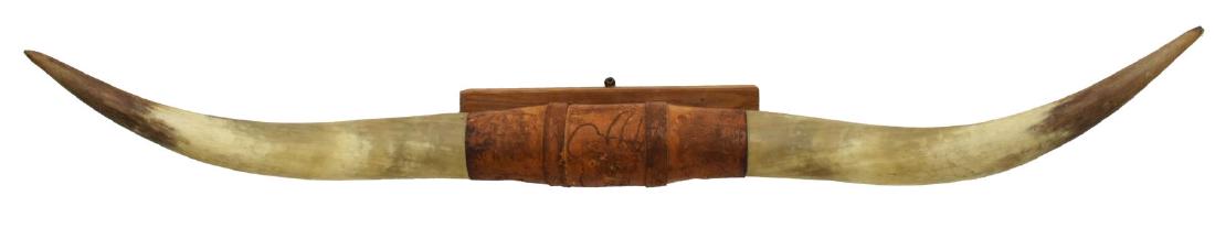 LARGE LONGHORN STEER TROPHY RACK HORNS, 47.75"L: Large longhorn steer trophy rack, the center wrapped in tooled leather with depiction of Brahman bull, approx 47.75"l, 5.25lbs Start Price: $100.00