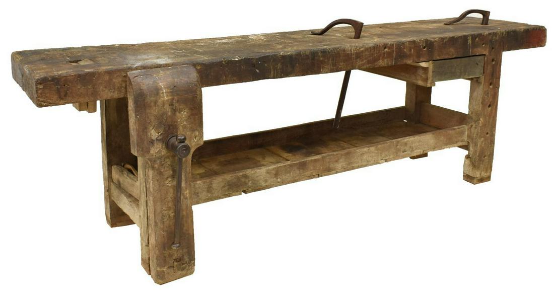 PRIMITIVE FRENCH CRAFTAMAN'S WORK BENCH TABLE: Primitive French craftsman's work bench table, the rectangular 4" top with drilled holes for tools, iron crank vise, rising on squared block supports joined by a lower storage shelf, approx 102"h, 24"