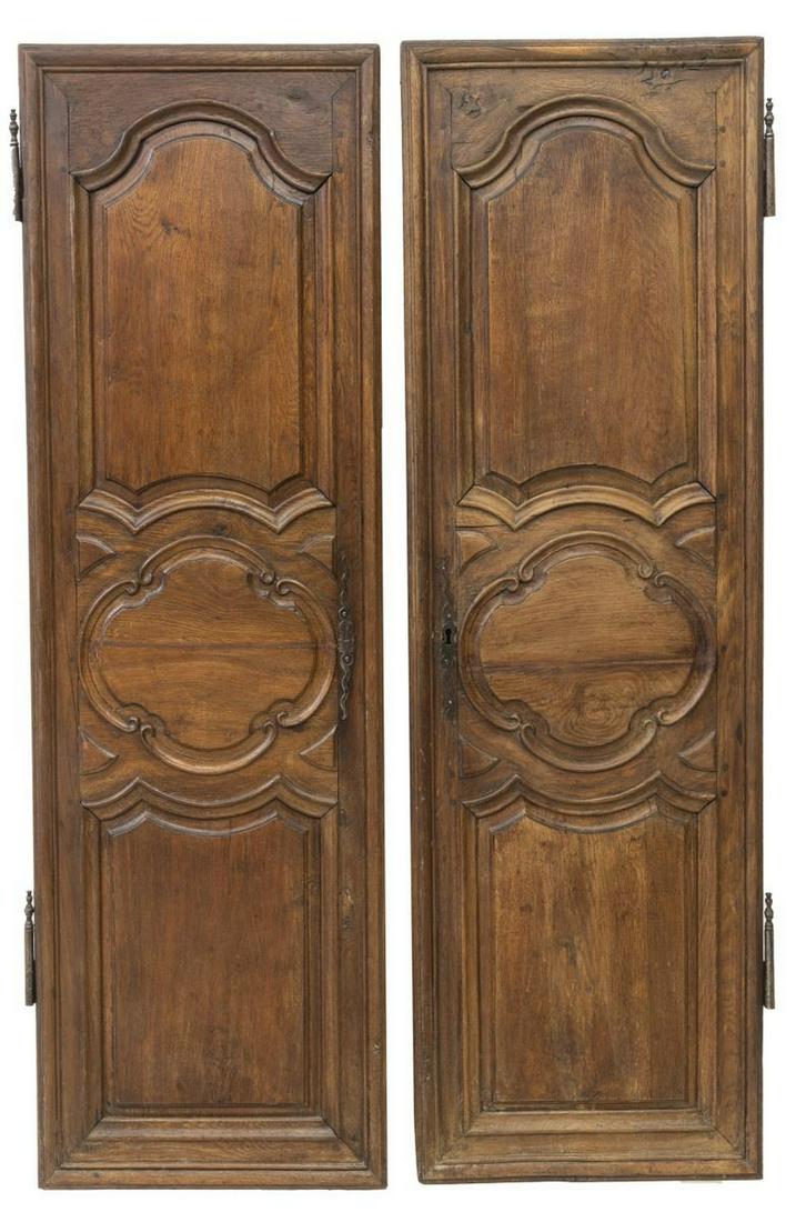 (2) FRENCH PROVINCIAL ARCHITECTURAL OAK DOORS: (lot of 2) French Provincial architectural oak doors, 19th c., paneled door, with decorative escutcheon, partial exterior hinges, approx 65.5"h, 22.5"w (measurements not including hinges) Start Price: