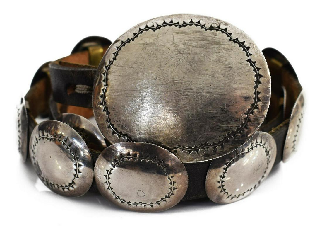 HARVEY BEAR TRACK TAOS PUEBLO SILVER CONCHO BELT: Estate Southwest silver (content unknown) and leather concho belt, signed Harvey Bear Track, Taos Pueblo, (1) worked oval buckle and (19) matched oval conchos, on a leather belt, surface abrasions to 