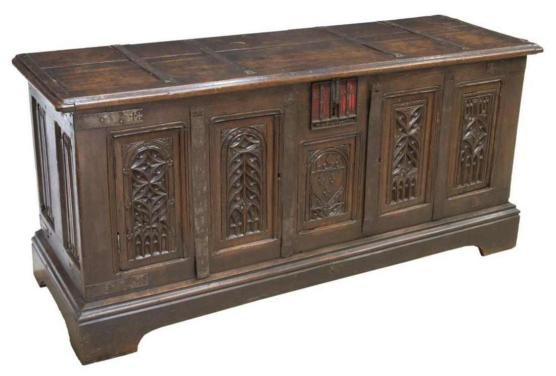 LARGE FRENCH GOTHIC REVIVAL CARVED OAK COFFER: Large French Gothic Revival carved oak coffer/ trunk, early 19th c., having rectangular top with iron hinges, opening to open storage, featuring incised design paneled front, rising on large block fee
