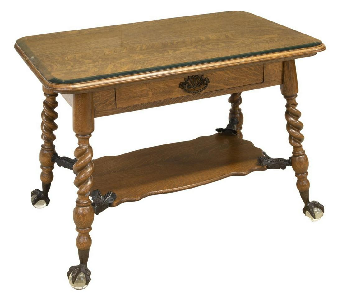 AMERICAN OAK BALL & TALON SPIRAL LIBRARY TABLE: Very fine American oak library table, c. 1890, the rectangular top with curved corners, under beveled glass surface, a single frieze drawer, rising on four spiraled legs, joined by a lower shelf with