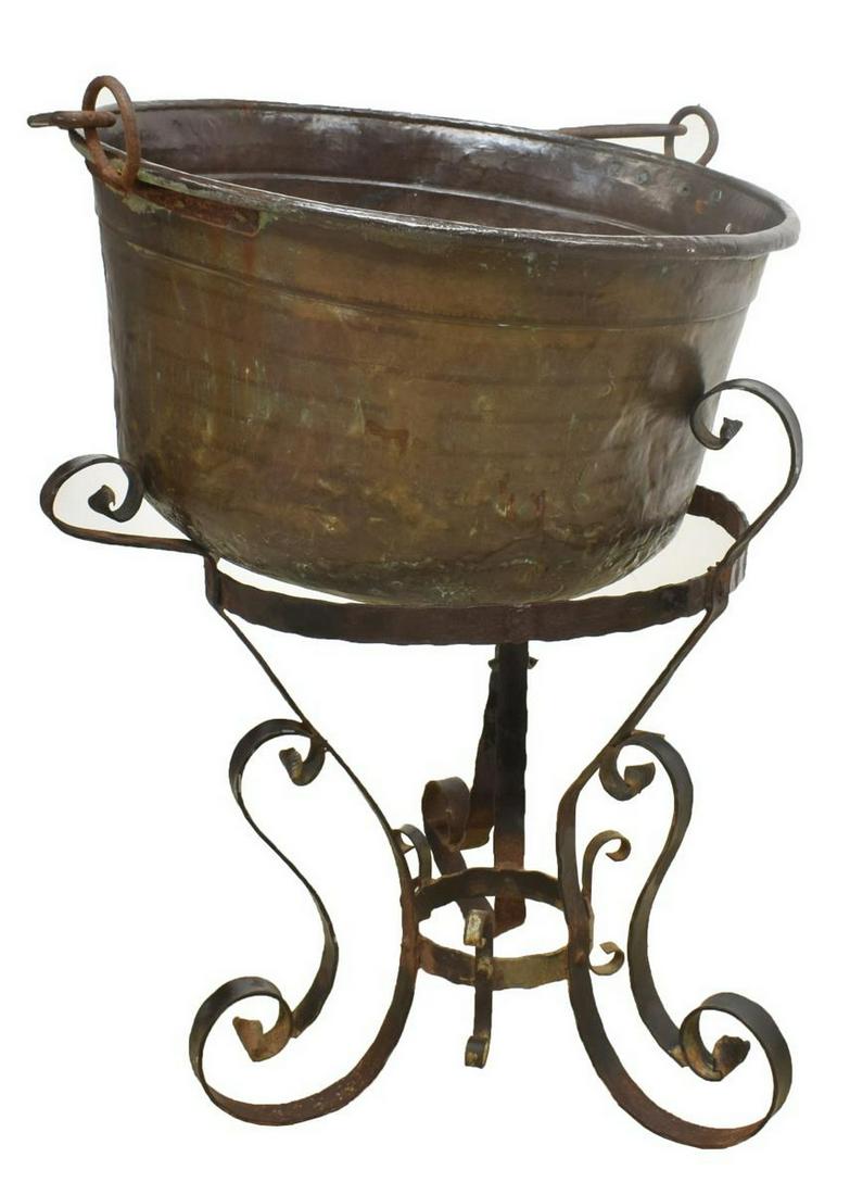 LARGE COPPER CAULDRON PLANTER ON IRON STAND: Large copper cauldron/ kettle, with iron bail handle, on scrolled wrought iron stand with bending, denting, overall: approx 38"h, 27.5"diam Start Price: $100.00