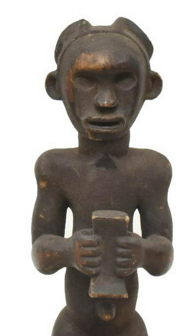 LARGE AFRICAN ANCESTRAL CARVED WOOD FIGURE: Large African ancestral carved wood figure, having dark pigment throughout, carved ears, nose and mouth, hollowed out eyes, bent arms and knees, rising on ebonized hexagonal base, approx 32"h, 10"w, 9