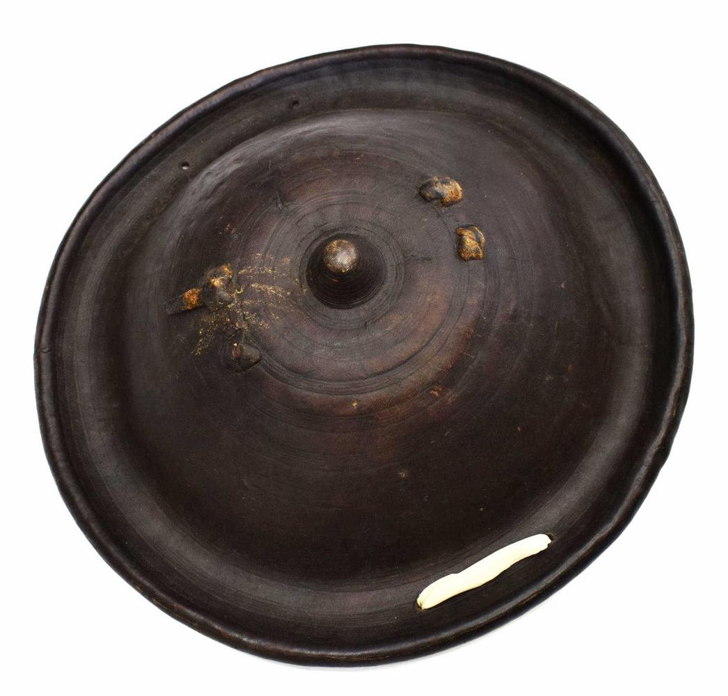 VINTAGE AFRICAN LEATHER CEREMONIAL SHIELD: Vintage African molded leather shield, Ethiopia, circular form, with central point, thick leather coating with applied handle at back, used for traditional funeral ceremonies, approx 6"h, 18.5"diam, 3