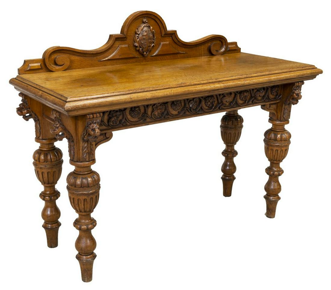 BRITISH RENAISSANCE REVIVAL SERVER CONSOLE: British Renaissance Revival oak server or console, late 19thc., having protruding lions heads at each corner, the raised back with central heraldic crest over the rectangular top, the skirt with appli