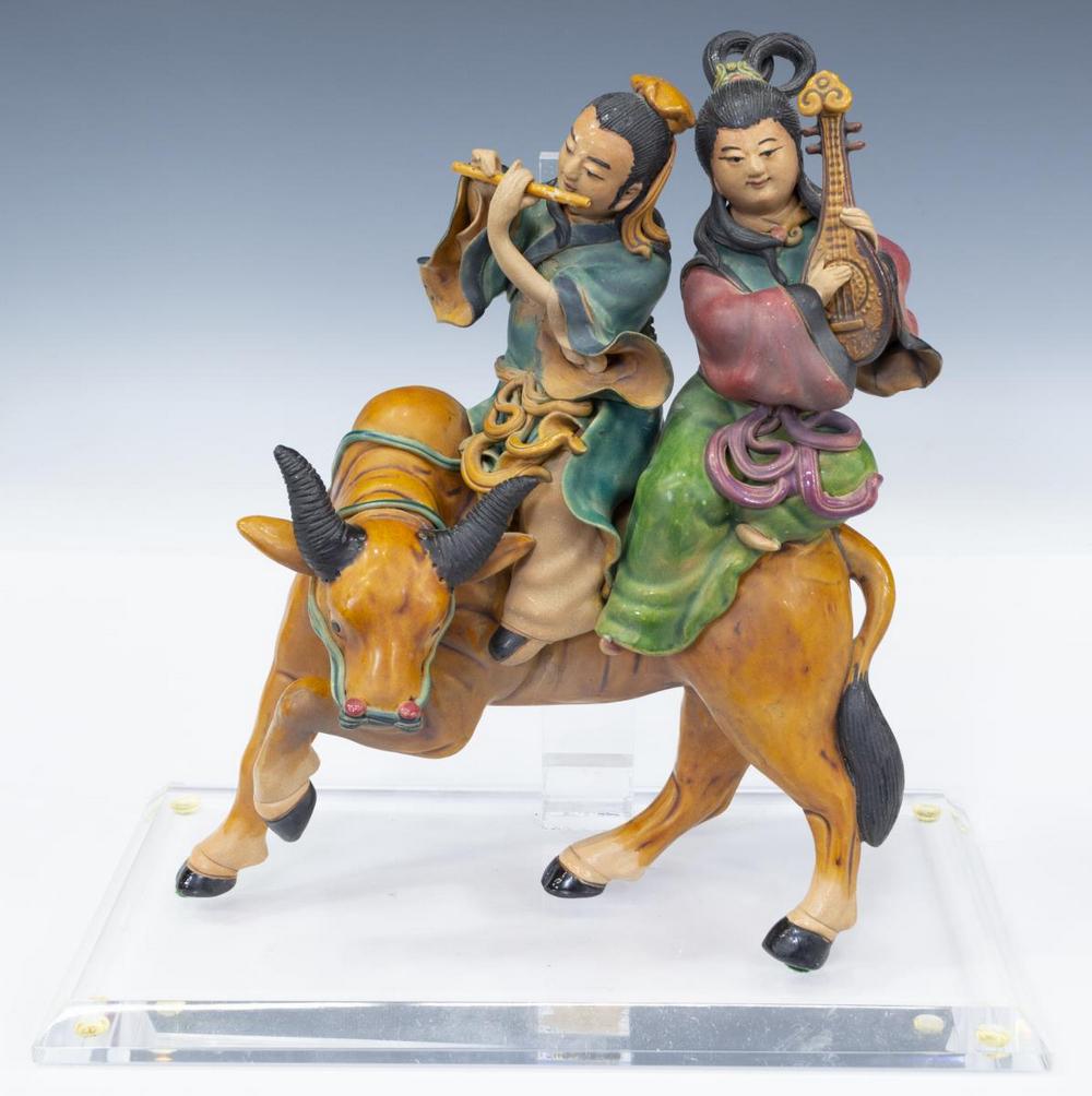 CHINESE PORCELAIN ROOF TILE, FIGURES ASTRIDE OX: Chinese porcelain roof tile, depicting male and female figure in traditional dress, each playing musical instrument, astride an ox, accompanied by lucite stand, restoration to male figure's instrument