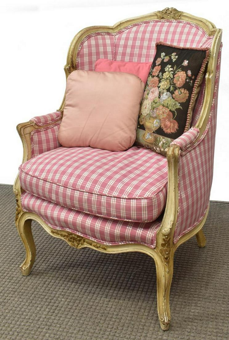 FRENCH LOUIS XV STYLE UPHOLSTERED BERGERE CHAIR: French Louis XV style armchair, early 20th c., white painted frame with carved floral crest, pink check plaid upholstery with cushion seat, closed arms, rising on cabriole legs, ending in whorl feet, 