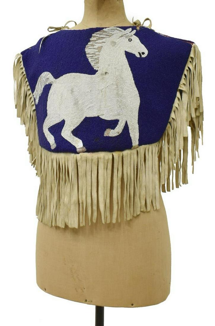 NATIVE AMERICAN PLATEAU DOUBLE-SIDED BEADED CAPE: Plateau beaded women's cape, third quarter 20th c., beaded on both sides with naturalistic running white horse against a blue ground, edges with fringe, approx 17"h, 16.75"w (all measurements taken fl